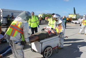 Aircraft Rescue Firefighters cart a simulated victim to the triage area as part of the Triennial Aircraft Disaster Exercise